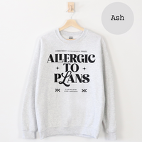 Flat lay of the Allergic to Plans sweatshirt in ash grey, unisex fit with bold black text — cozy and minimal design.