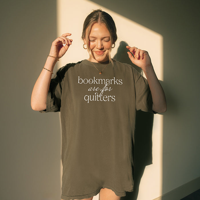 Woman wearing pepper “Bookmarks Are for Quitters” tee indoors – cozy oversized reading graphic tee for book lovers