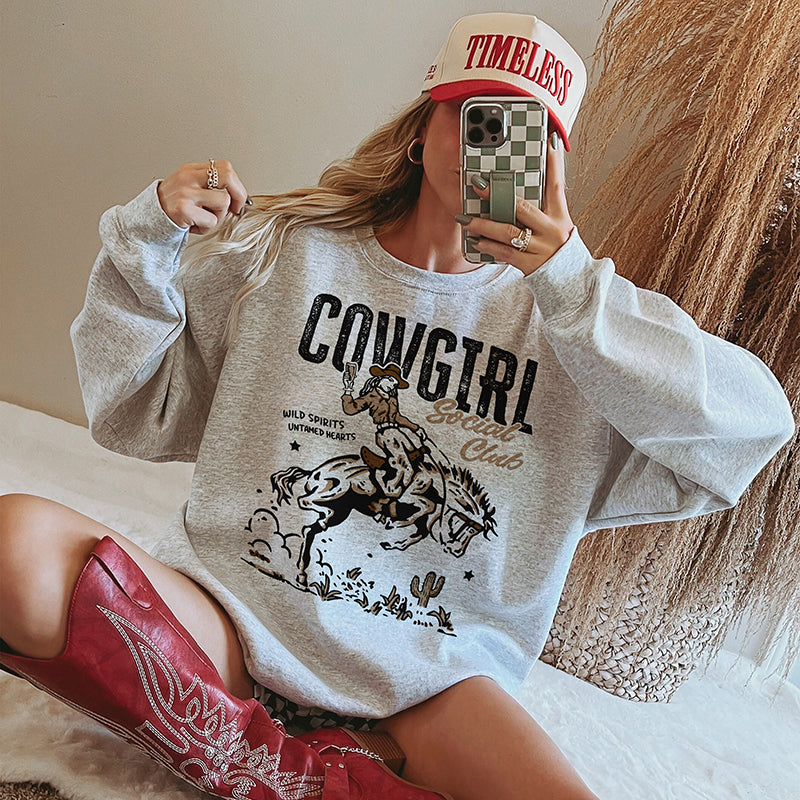 Model in ash crewneck styled with cowgirl boots and baseball cap — western sweatshirt outfit