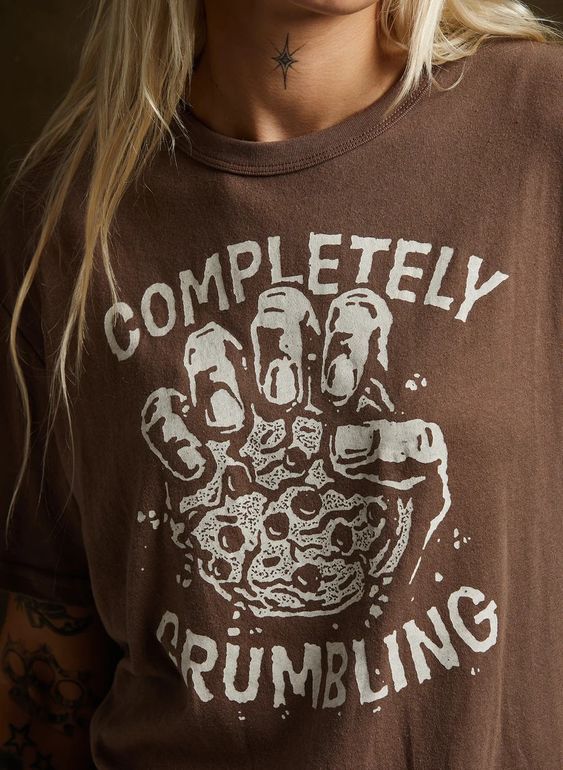 Close-up of female model wearing Pyknic's Completely Crumbling tee, featuring cookie graphic. Casual outfit with black jeans.