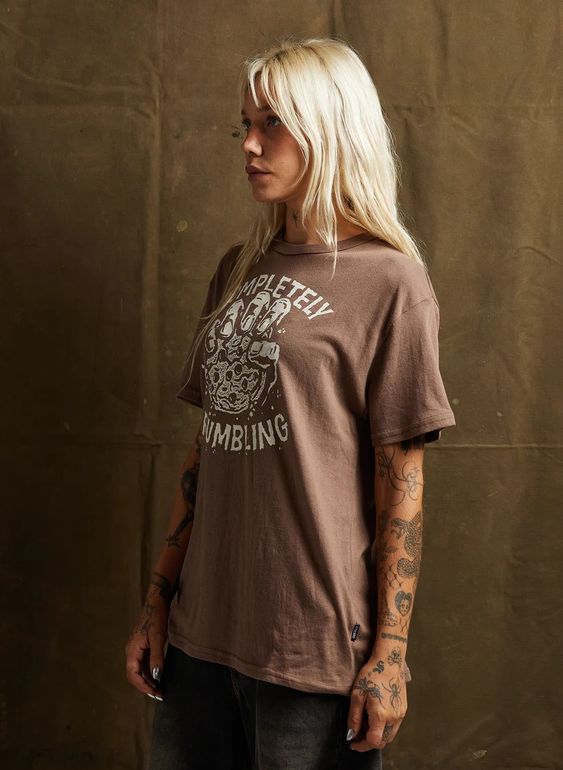 Woman in black jeans and vintage-style tee with crumbling cookie design. Pyknic brand unisex fit shirt for everyday wear.
