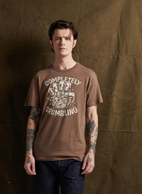 Man in jeans modeling Pyknic’s Completely Crumbling tee. Features cookie graphic and relaxed, casual fit.