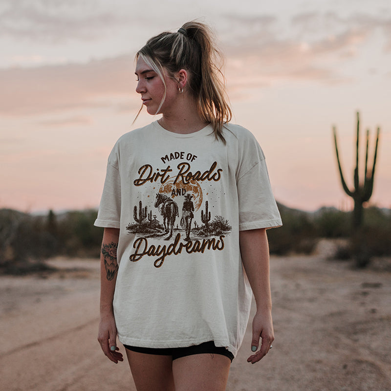 Model standing in desert wearing Made of Dirt Roads and Daydreams tee — boho western graphic shirt for women