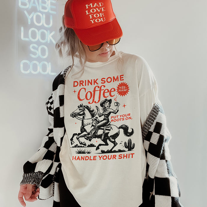 Model wearing Drink Some Coffee tee with trucker hat and cardigan — western coffee graphic tee for women