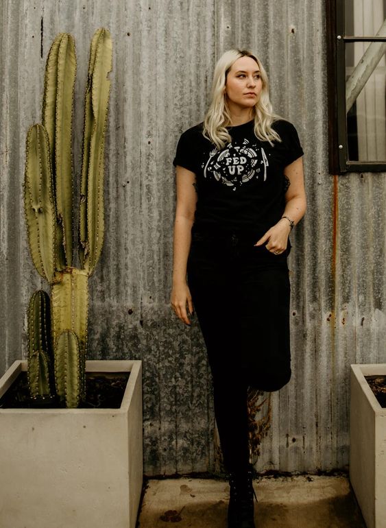 Full body shot of blonde model wearing Fed Up tee with black pants and boots. Casual, unisex fit with bold broken plate graphic.