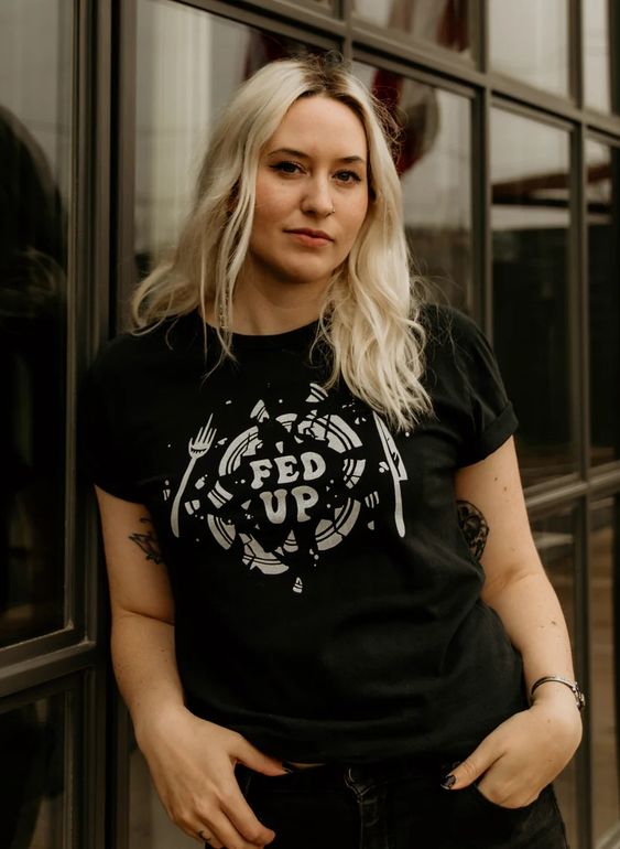Blonde model in Fed Up tee. Black cotton shirt with broken plate design and “Fed Up” text.