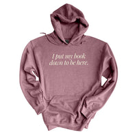 Flat lay of heather dark maroon “I Put My Book Down To Be Here” hoodie – cozy book lover hoodie for introverts and readers