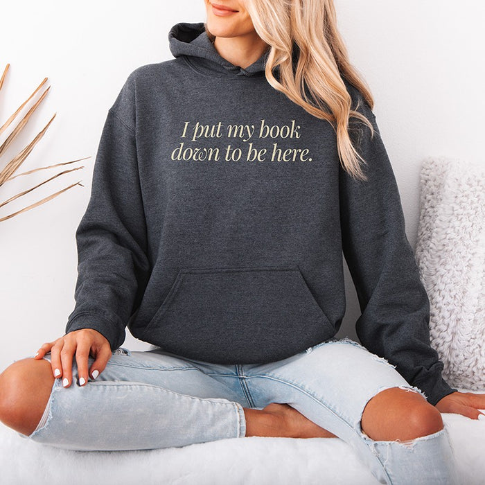 Woman wearing dark heather “I Put My Book Down To Be Here” hoodie – soft unisex reading hoodie for book lovers