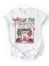 Flat lay of North Pole Readers Club Christmas book lover tee — cozy holiday graphic shirt for readers