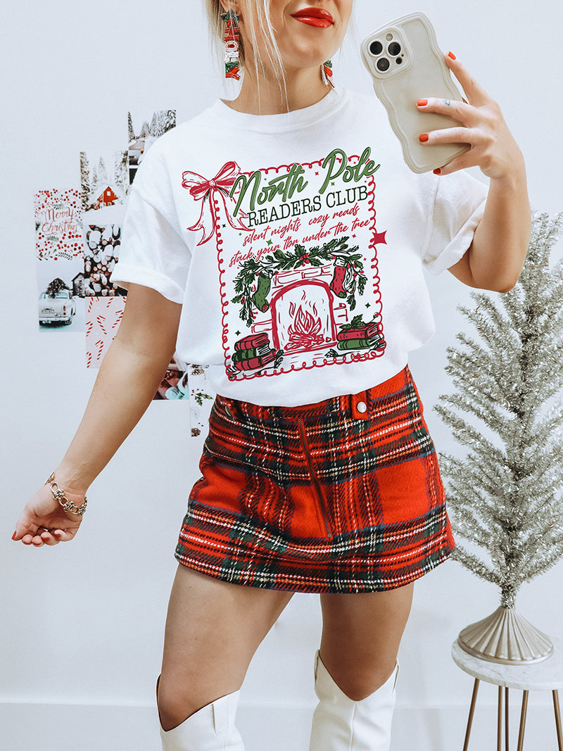 Heavyweight vintage-style Christmas tee for book lovers — North Pole Readers Club design with greenery and fireplace
