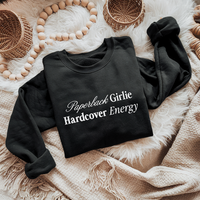 Flat lay of the Paperback Girlie Hardcover Energy sweatshirt in black (Bella Canvas style) — bold bookish graphic on ultra-soft fleece.

