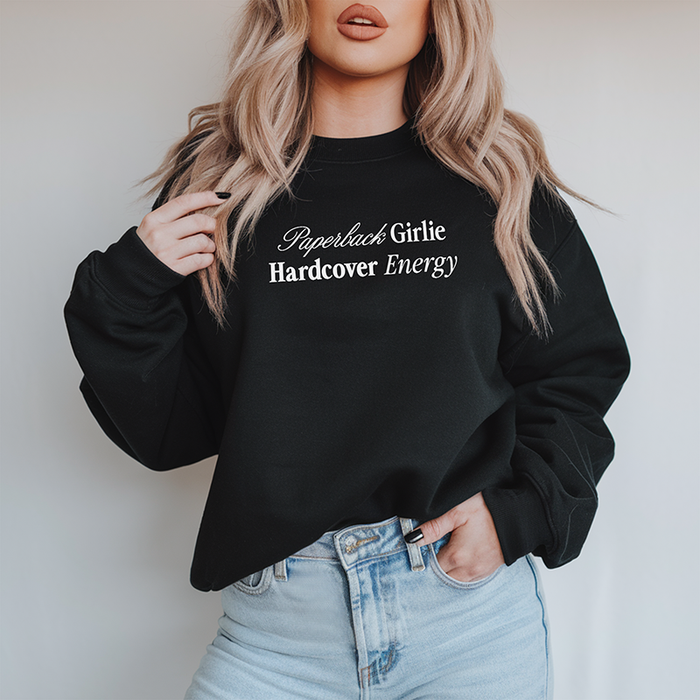 Woman wearing the Paperback Girlie Hardcover Energy sweatshirt (Bella Canvas style) with jeans — soft, relaxed, main character energy.