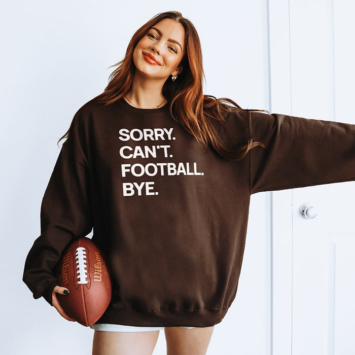 Woman wearing dark chocolate “Sorry. Can’t. Football. Bye.” sweatshirt — cozy unisex fleece crewneck for football fans and game days.