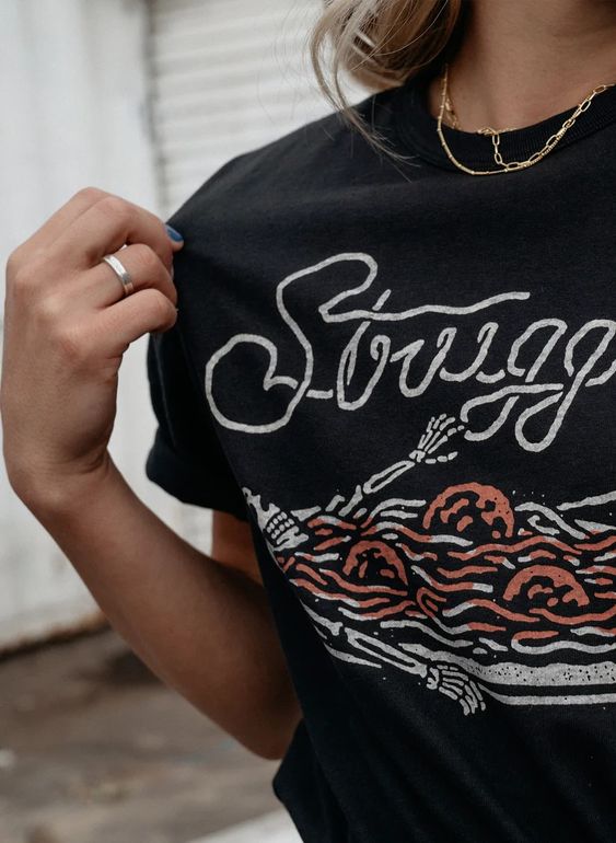 Detail shot of the Strugglin’ graphic tee. Shows skeleton and spaghetti design on black cotton shirt.
